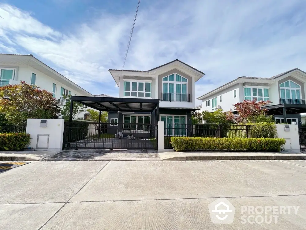 Modern two-story house with large windows and driveway in a suburban neighborhood.