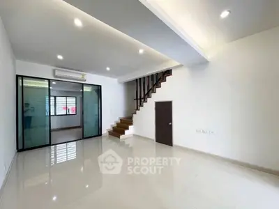 Spacious modern living room with sleek staircase and glass partition, perfect for contemporary living.