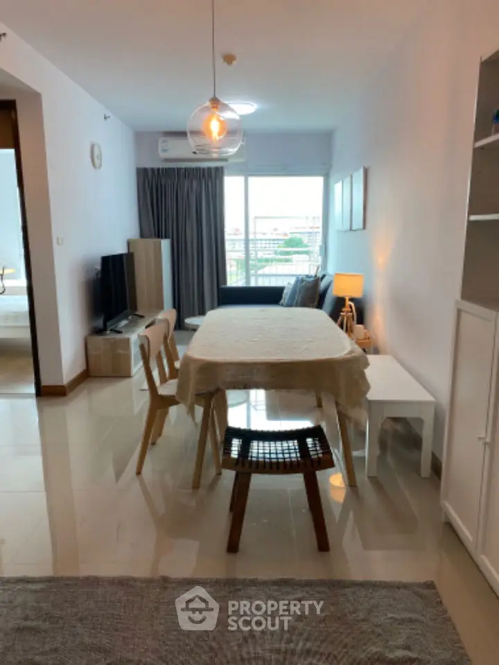 Modern living room with dining area, stylish furniture, and natural light from large window.