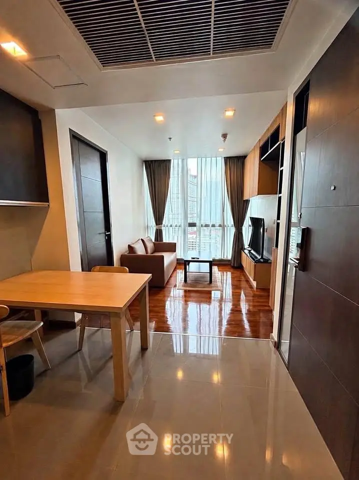 Modern living room with sleek furniture and large window offering city views.