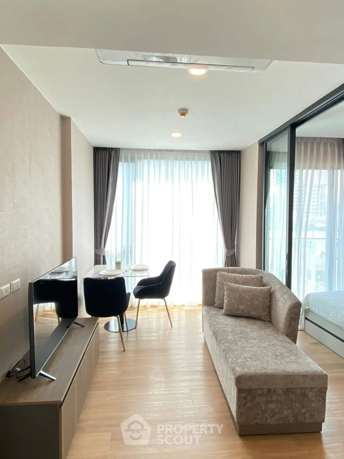 Modern living room with stylish furniture and large windows offering city views.