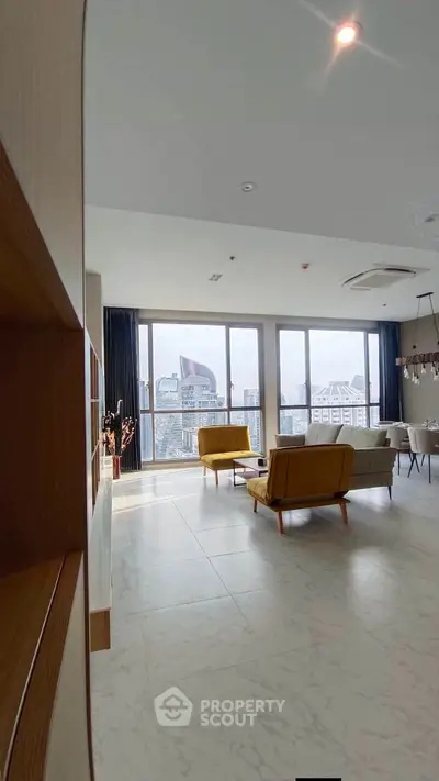 Spacious modern living room with large windows offering a stunning city view, featuring stylish furniture and elegant decor.