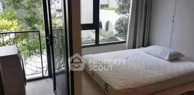 Modern bedroom with balcony access and large windows offering natural light.
