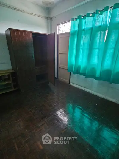 Spacious room with wooden flooring and bright teal curtains