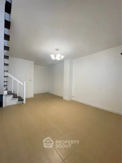 Spacious empty room with staircase and modern lighting, ideal for customization.