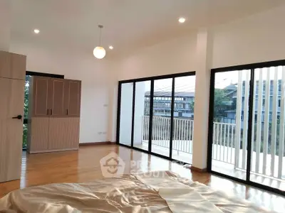 Spacious bedroom with large windows and balcony access in modern apartment