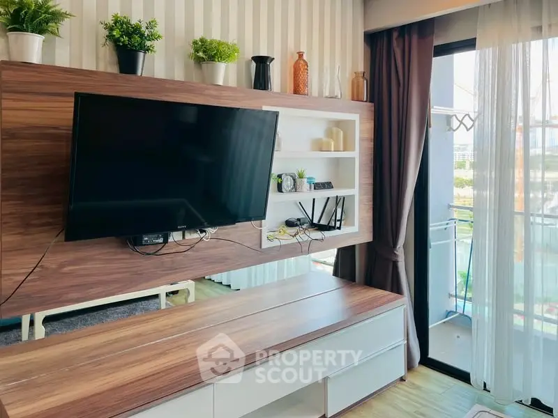 Modern living room with wall-mounted TV and balcony access, featuring stylish decor and natural light.