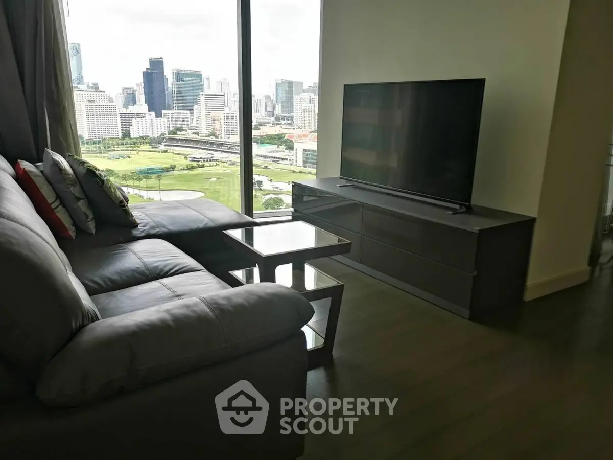 Modern living room with city view, featuring sleek furniture and large window.