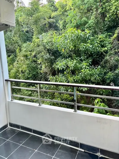 Charming balcony with lush green forest view, perfect for relaxation and enjoying nature.
