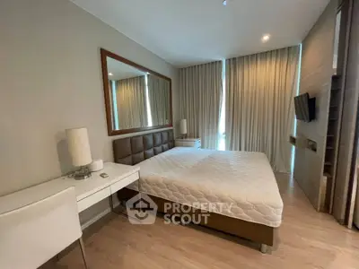 Modern bedroom with stylish decor and large mirror, featuring a comfortable bed and elegant lighting.