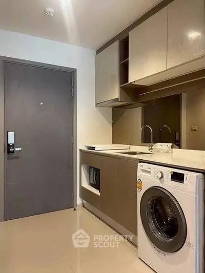 Modern laundry room with sleek cabinetry and washing machine in stylish apartment.