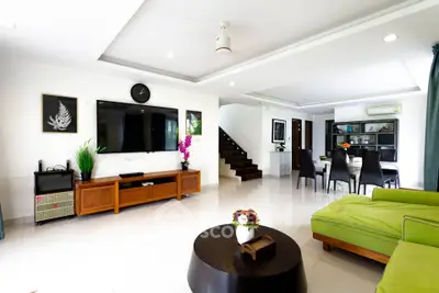 Spacious modern living room with green sofa, dining area, and stylish decor in open layout.