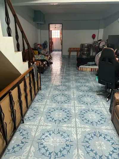 Spacious living area with unique patterned tile flooring and staircase, ideal for customization.