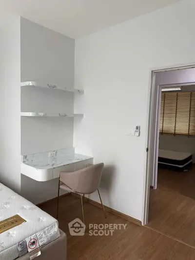 Modern bedroom with sleek desk and chair, featuring minimalist design and wooden flooring.