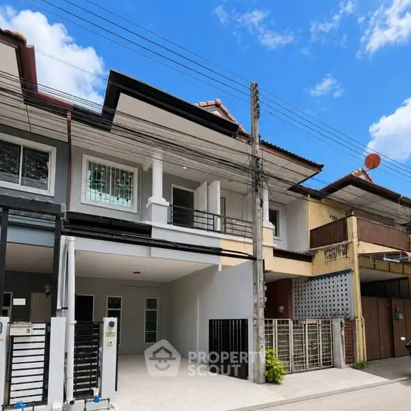 Modern townhouse exterior with gated entrance and clear blue sky.