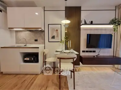 Modern open-plan living room with stylish kitchen and dining area, featuring sleek furniture and elegant decor.