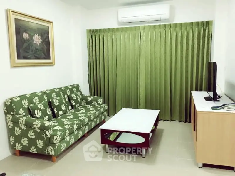 Cozy living room with green sofa and curtains, air conditioning, and modern decor.
