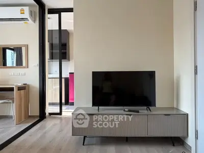 Modern living room with sleek TV stand and open kitchen layout in stylish apartment.