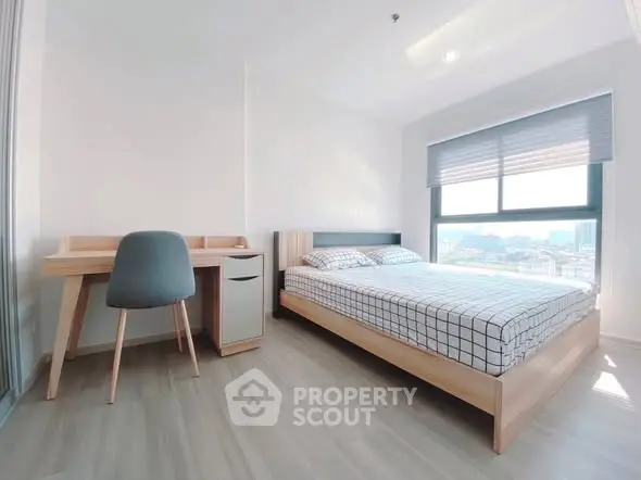 Modern bedroom with large window and stylish furniture in a bright apartment.