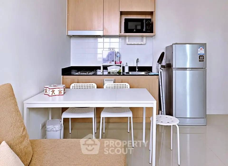 Modern compact kitchen with dining area and stainless steel fridge in cozy apartment.