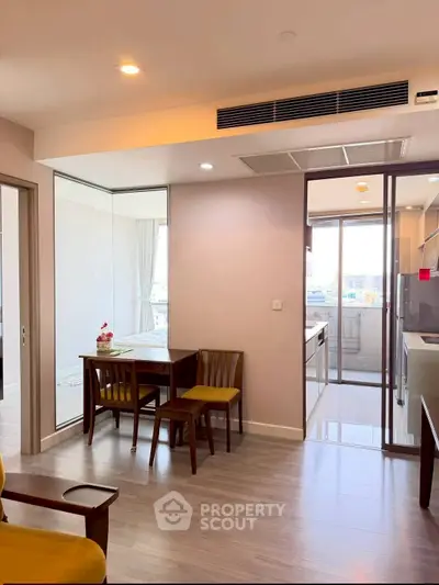 Modern apartment interior with open layout and dining area, featuring sleek kitchen design and large windows.