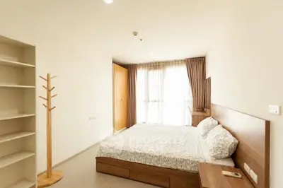 Spacious bedroom with natural light and modern wooden furniture