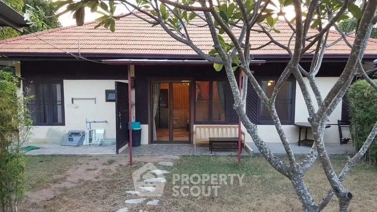 Charming single-story house with a red-tiled roof and lush garden, perfect for serene living.