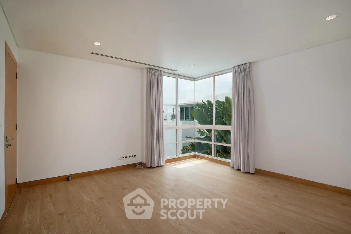 Spacious empty room with large windows and wooden flooring, perfect for customization.