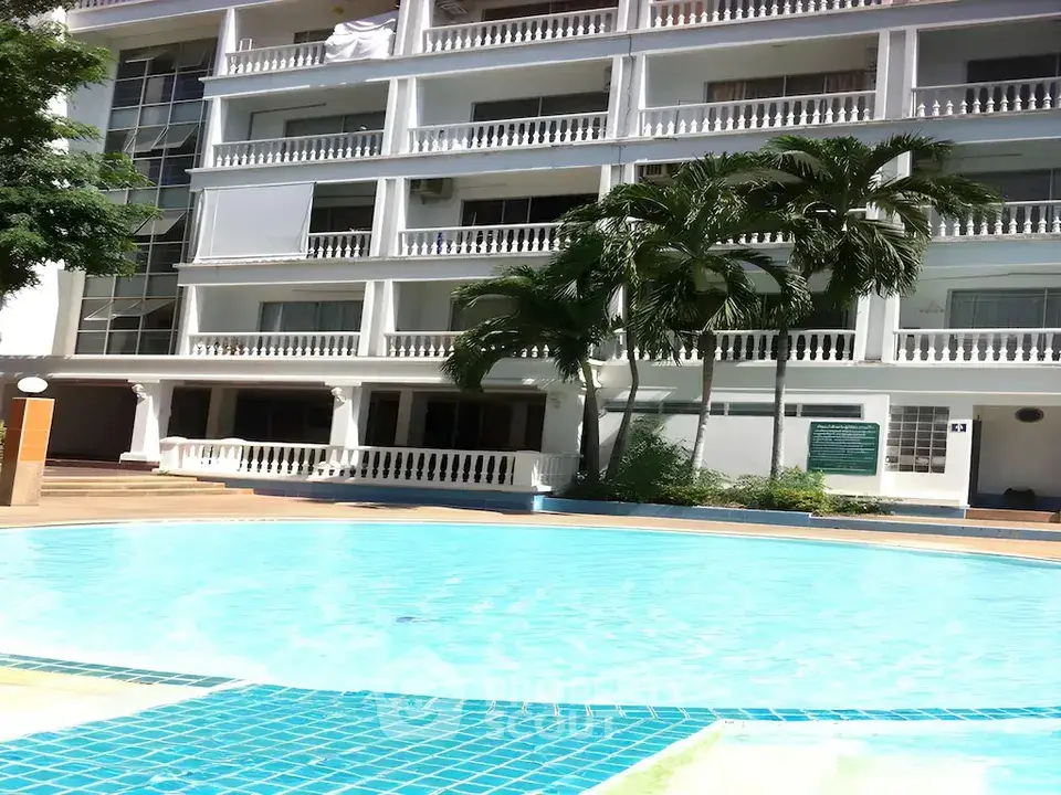 Luxurious apartment building with a stunning pool and lush palm trees, perfect for resort-style living.