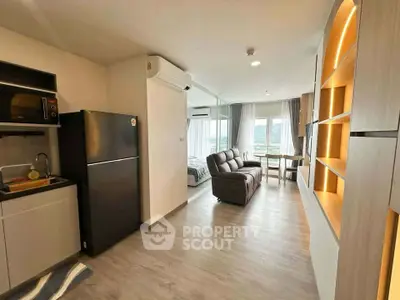 Modern open-plan living room with kitchen and cozy seating area, featuring sleek design and ample natural light.