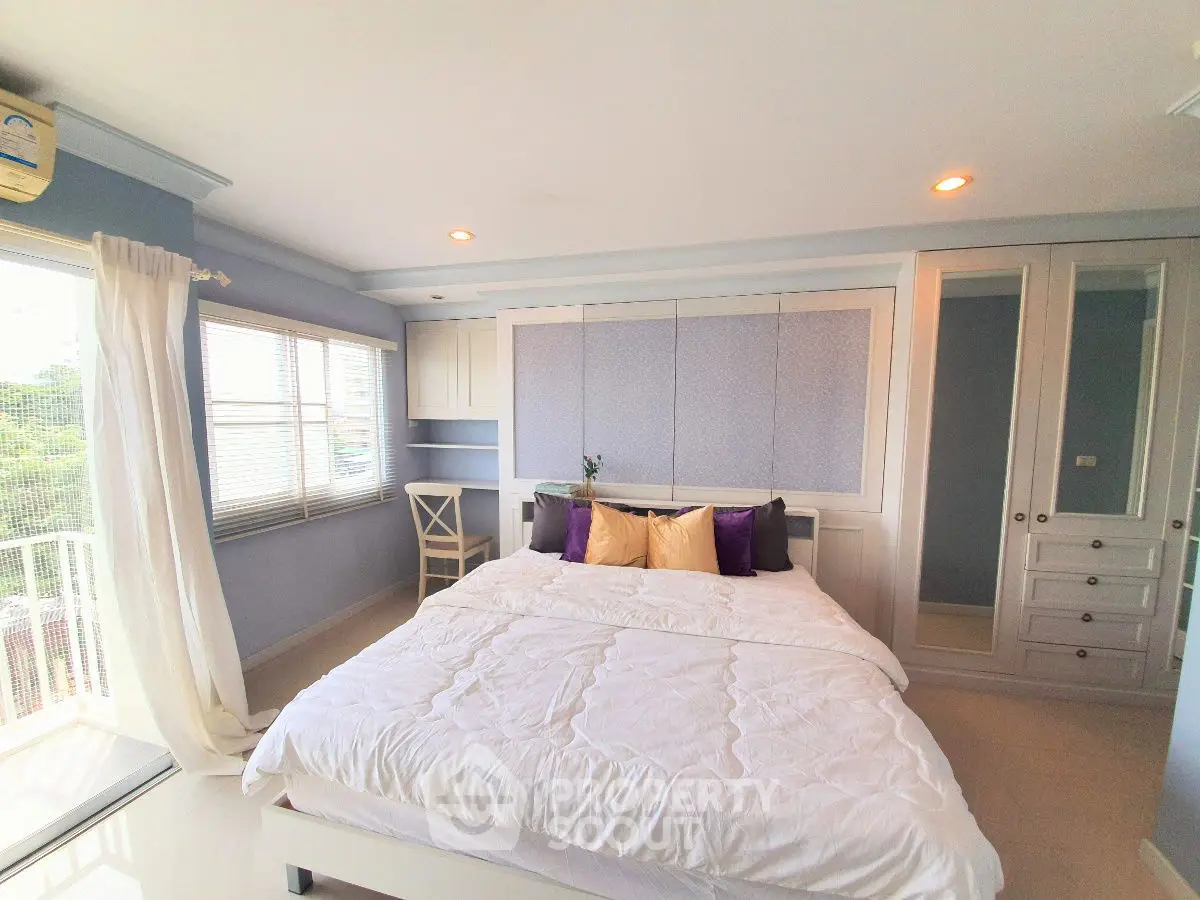 Spacious bedroom with elegant decor and large windows offering natural light and scenic views.