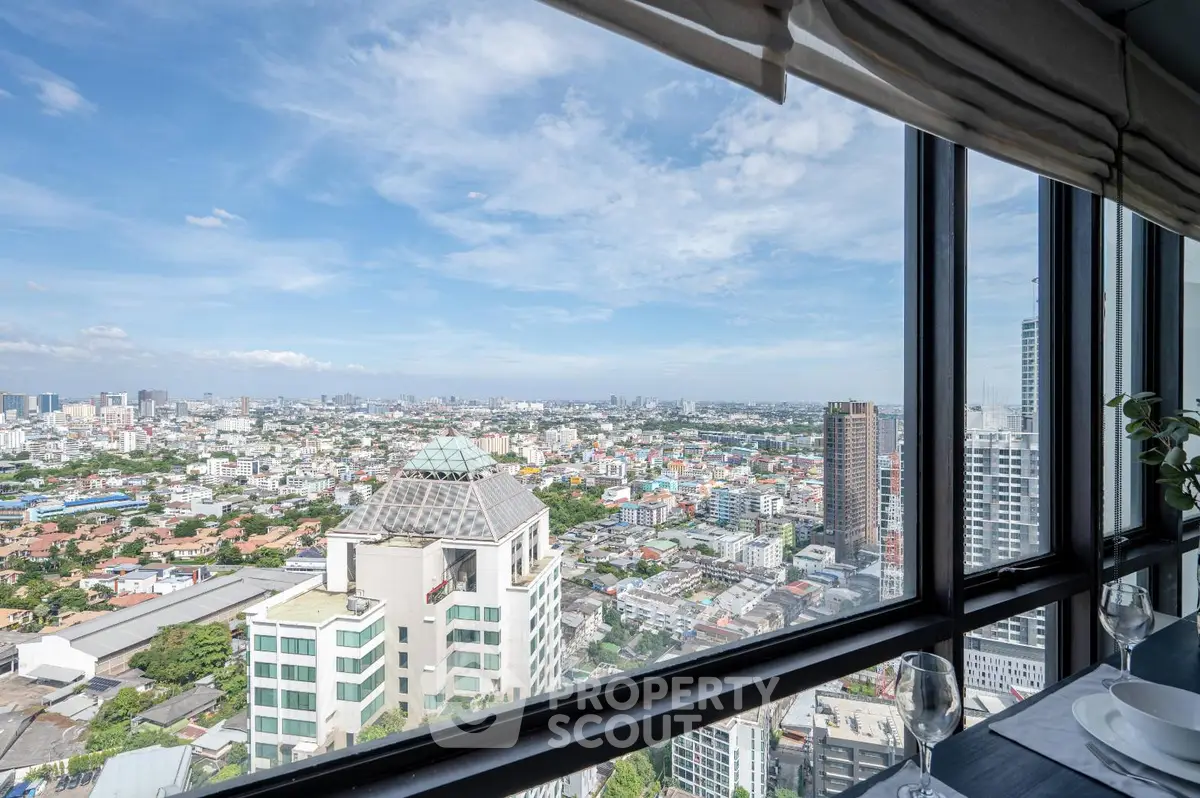 Stunning cityscape view from high-rise apartment window with clear blue sky.