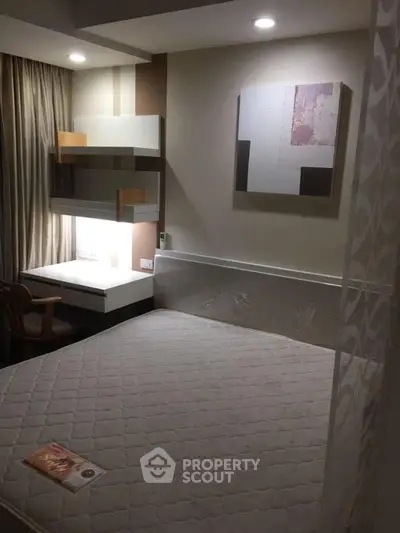 Modern bedroom with cozy lighting and stylish decor, featuring a comfortable bed and a functional study area.