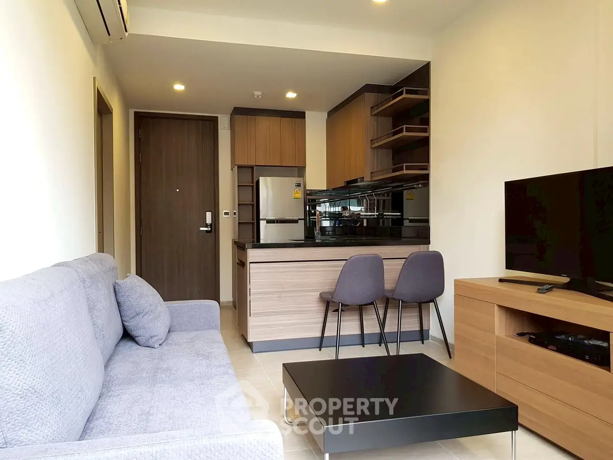 Modern living room with open kitchen, featuring sleek furniture and contemporary design.