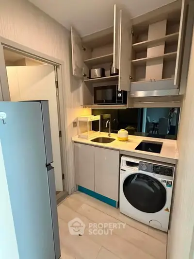 Compact modern kitchen with built-in appliances and washing machine in a stylish apartment.