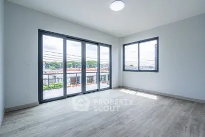 Spacious corner unit with large windows and balcony access, offering abundant natural light and modern flooring.