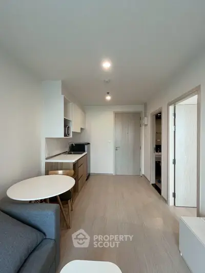 Modern apartment interior with open kitchen and cozy living area, featuring sleek furniture and minimalist design.