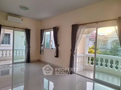 Spacious sunlit room with large windows and balcony access in a modern home.