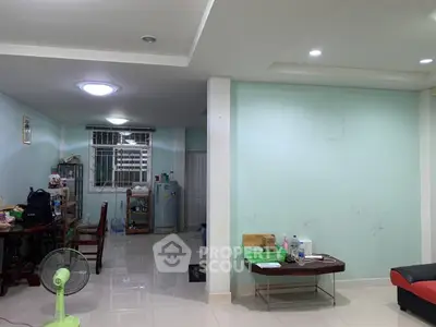 Spacious living area with modern lighting and tiled flooring, featuring a dining table and refrigerator.