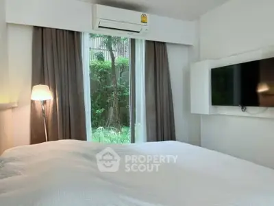 Cozy bedroom with garden view, featuring modern decor and wall-mounted TV, perfect for relaxation.