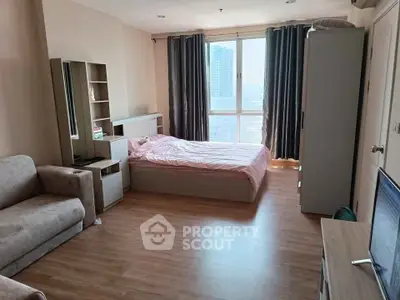 Spacious bedroom with modern furnishings and large window offering city view.