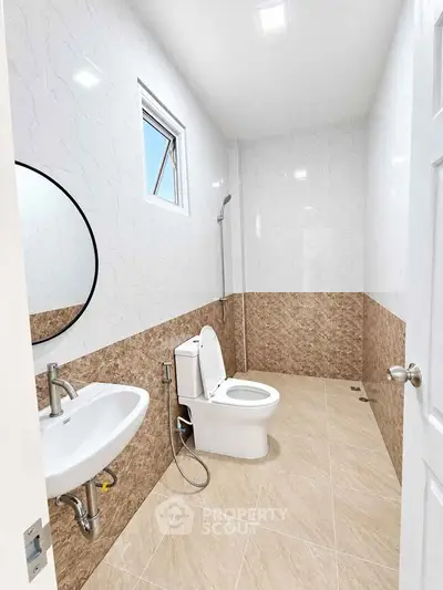 Modern bathroom with elegant tile design and round mirror, featuring a sleek toilet and sink.