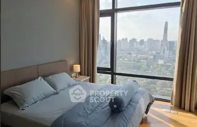 Luxurious bedroom with stunning city skyline view from floor-to-ceiling windows.