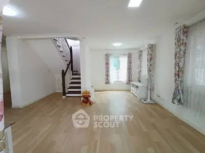 Spacious living room with wooden flooring and floral curtains in a bright home.