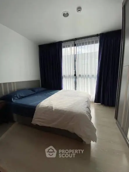 Cozy bedroom with large window and elegant curtains, perfect for relaxation.