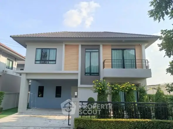 Modern two-story house with balcony and landscaped garden in a serene neighborhood.