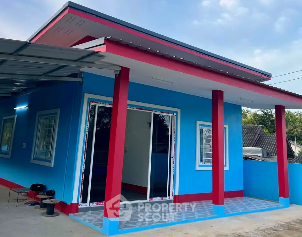 Vibrant blue and red modern house exterior with sliding glass doors and tiled patio.