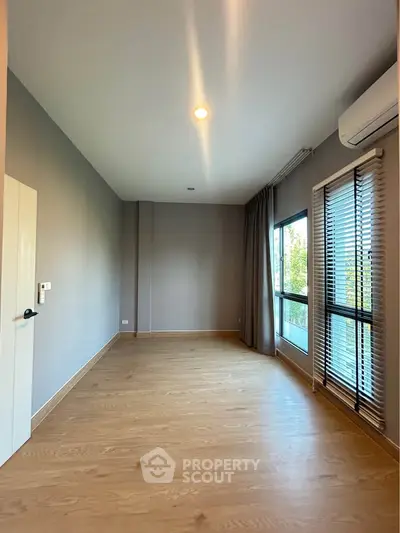 Spacious empty room with large windows and wooden flooring, perfect for customization.