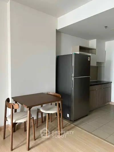 Modern kitchen with dining area featuring sleek fridge and wooden table set.