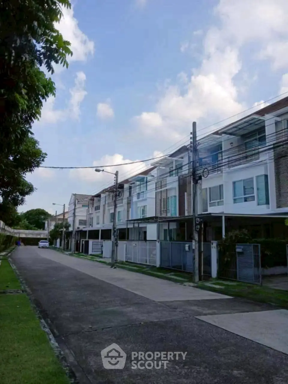 Modern townhouse exterior with clean lines and lush greenery on a quiet street.